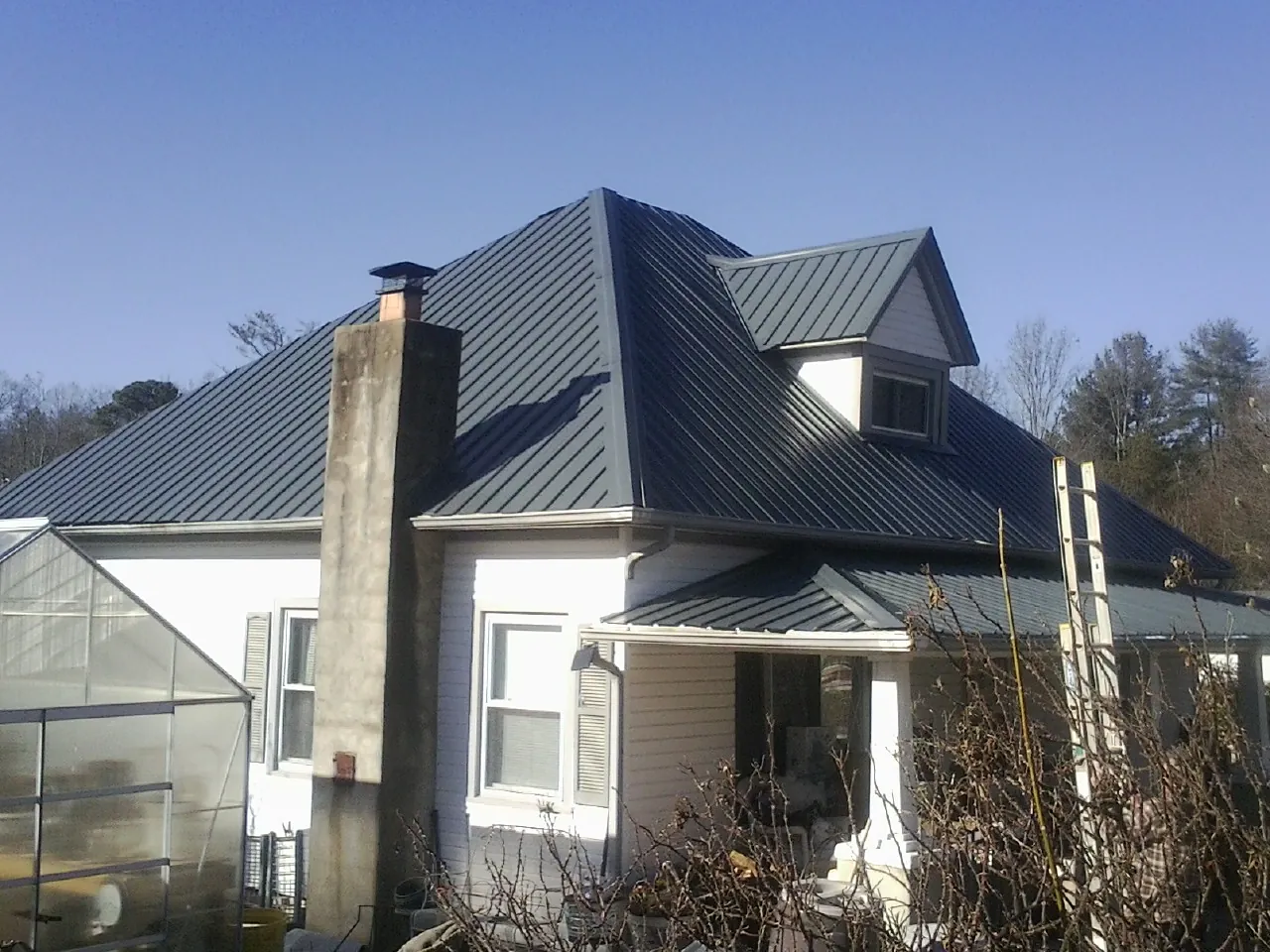 Dark blue standing seam metal roof on a white farmhouse with dormer — Slate & Tile Roof Repair by Roofing Brothers in Ivor