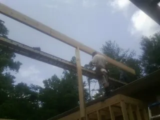 Carpenter setting a ridge beam over a new addition frame — Ice Dam Removal by Roofing Brothers in Ivor