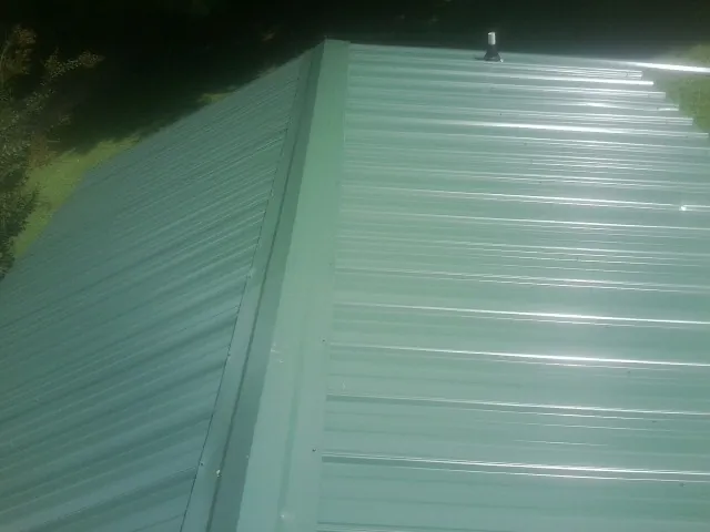 New green metal panels meeting at the ridge of a roof — Flat Roof Repair work by our crew in Ivor