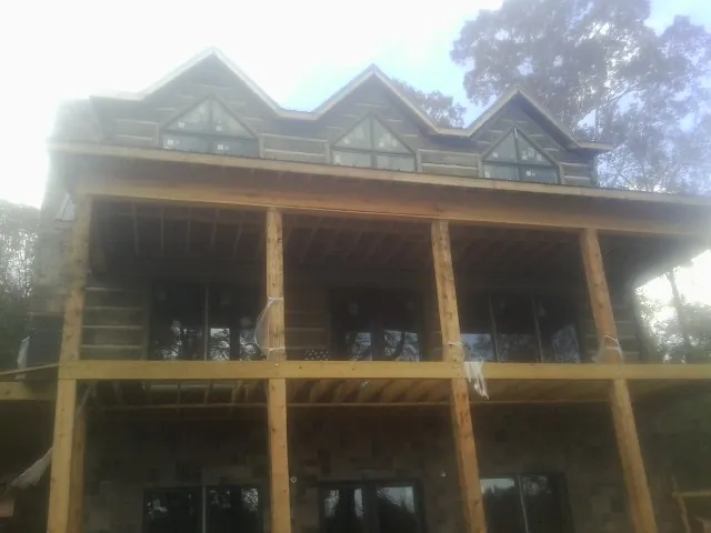 Dormers and porch framing on a large log home under construction — Roof Coating work by our crew in Ivor