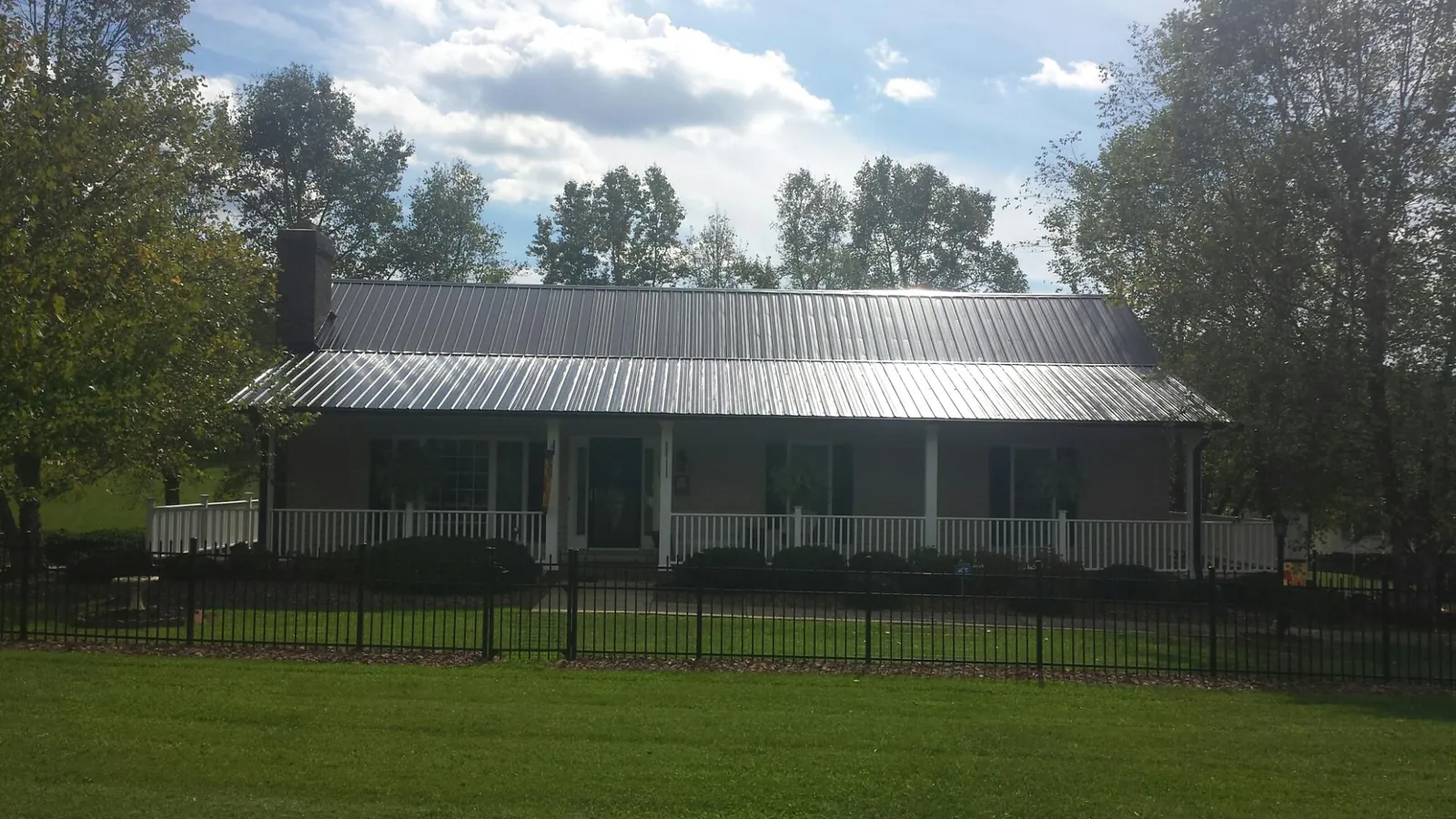 Gray metal roof on a brick ranch with a full width front porch — Gutter Guard Installation work by our crew in Ivor