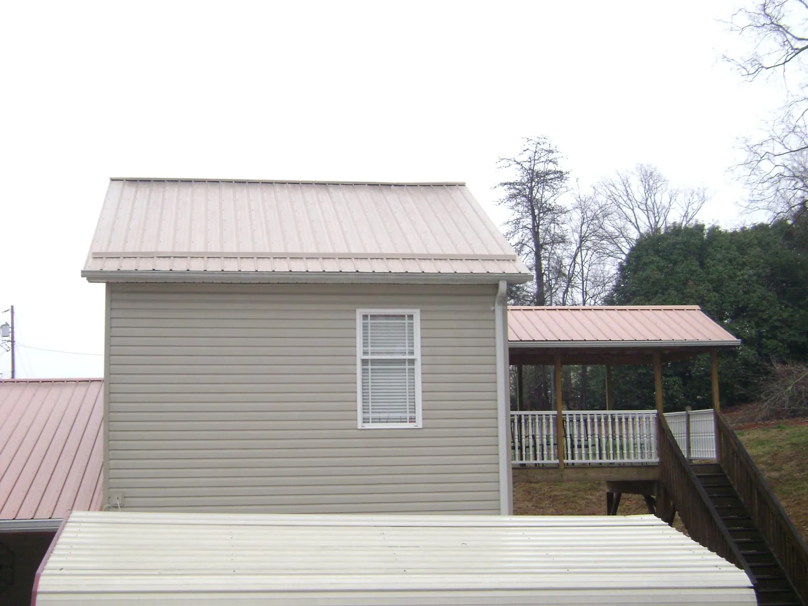 Tan metal roofs on a two story addition and attached porch, from a Roof Replacement job in Ivor