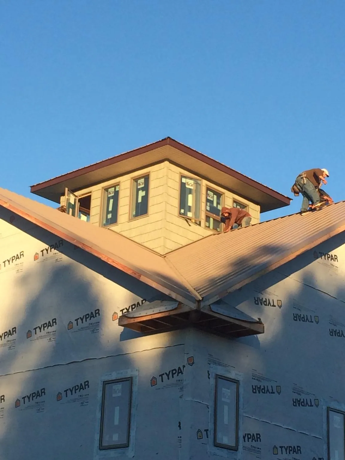 Roofers working around a rooftop cupola on a new metal roof at sunset — Roof Waterproofing in Ivor by Roofing Brothers